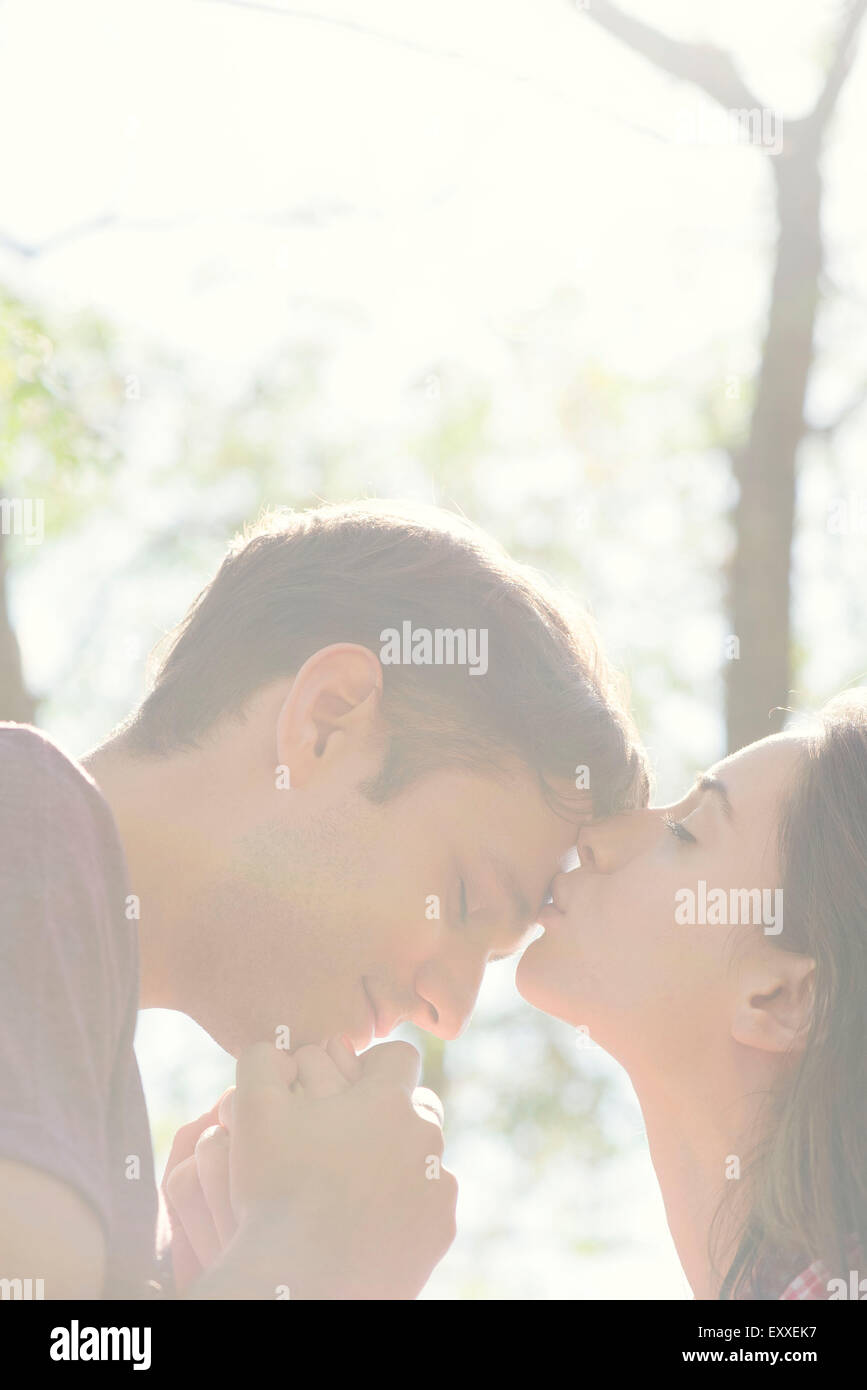Couple together outdoors, woman kissing man's forehead Stock Photo