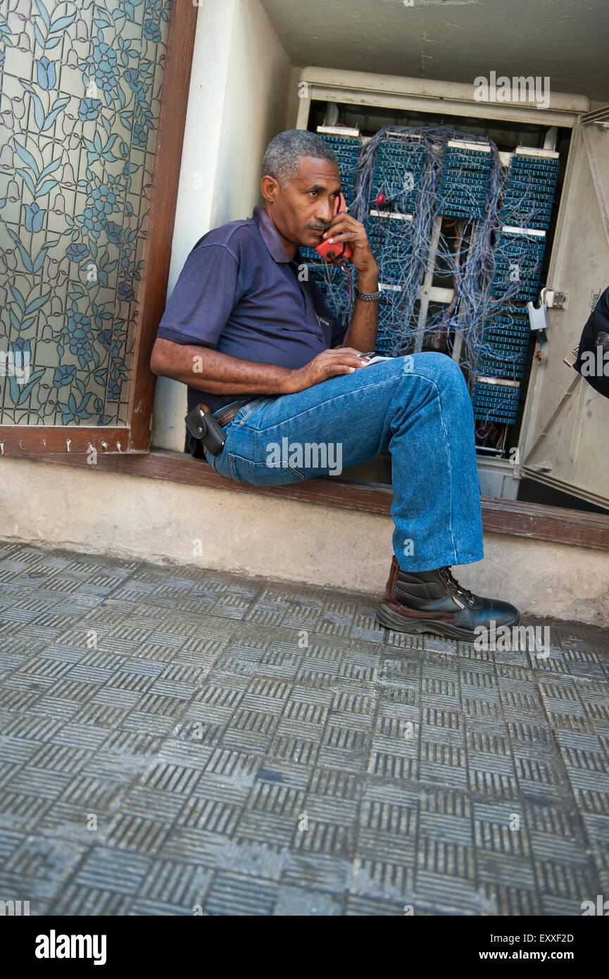 HAVANA, CUBA - MAY 16, 2011: Cuban telephone technician sits inside a junction box testing connections on the street. Stock Photo