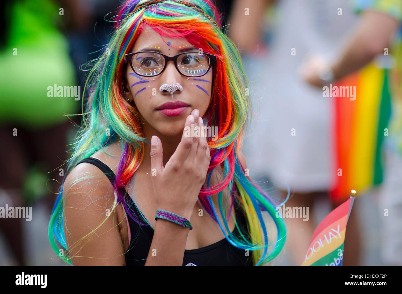 NEW YORK CITY, USA - JUNE 28, 2015: Young woman dressed in colorful wig looks at the festivities of the annual Pride Parade. Stock Photo