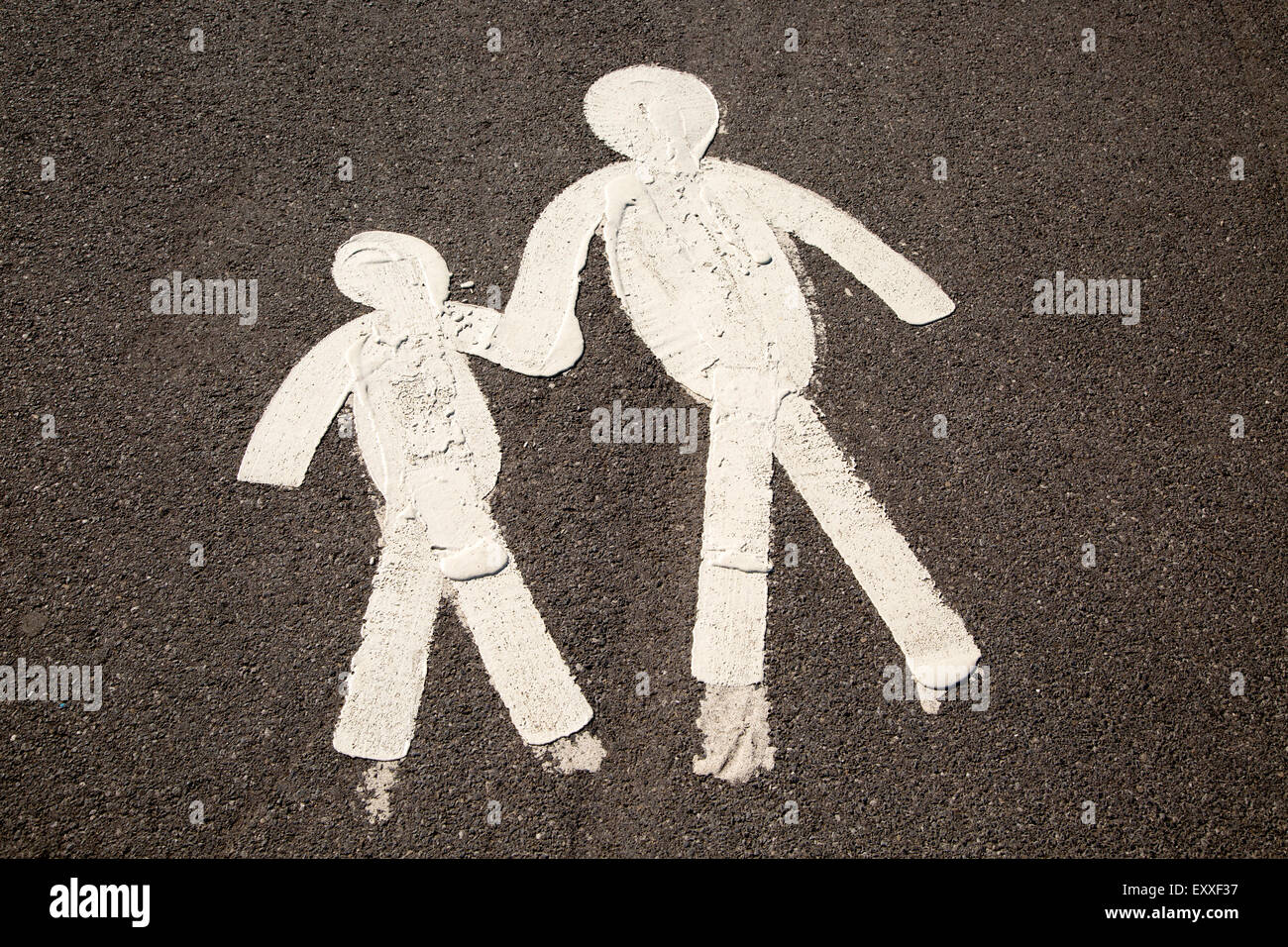 Child and parent  figures holding hands on tarmac pavement, Mumbles, South Wales, UK Stock Photo