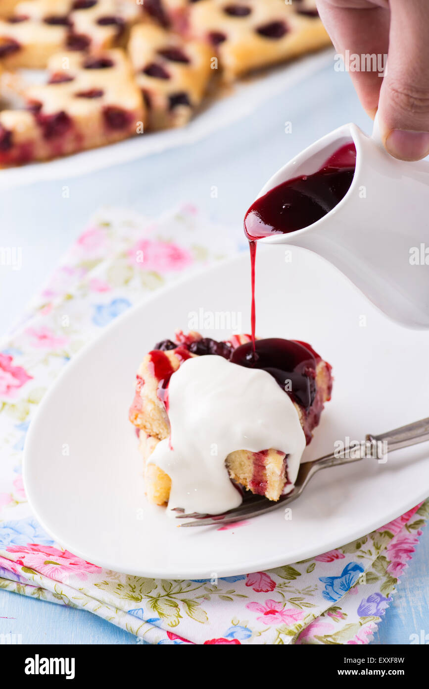 Homemade cherry cake with cream and pouring sauce on plate, selective focus Stock Photo