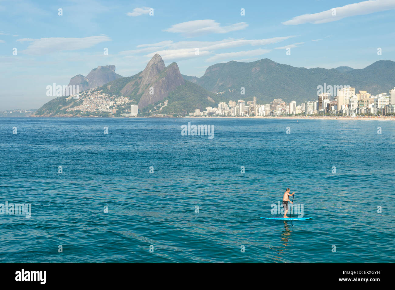 RIO DE JANEIRO, BRAZIL - MARCH 22, 2015: A pair of stand up paddle enthusiasts make their way along the water at Arpoador. Stock Photo