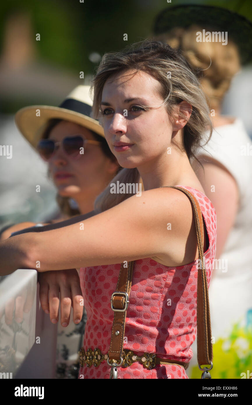Female spectator in summer dress at a fenced railing watching a horse race at Hastings Park Vancouver Stock Photo