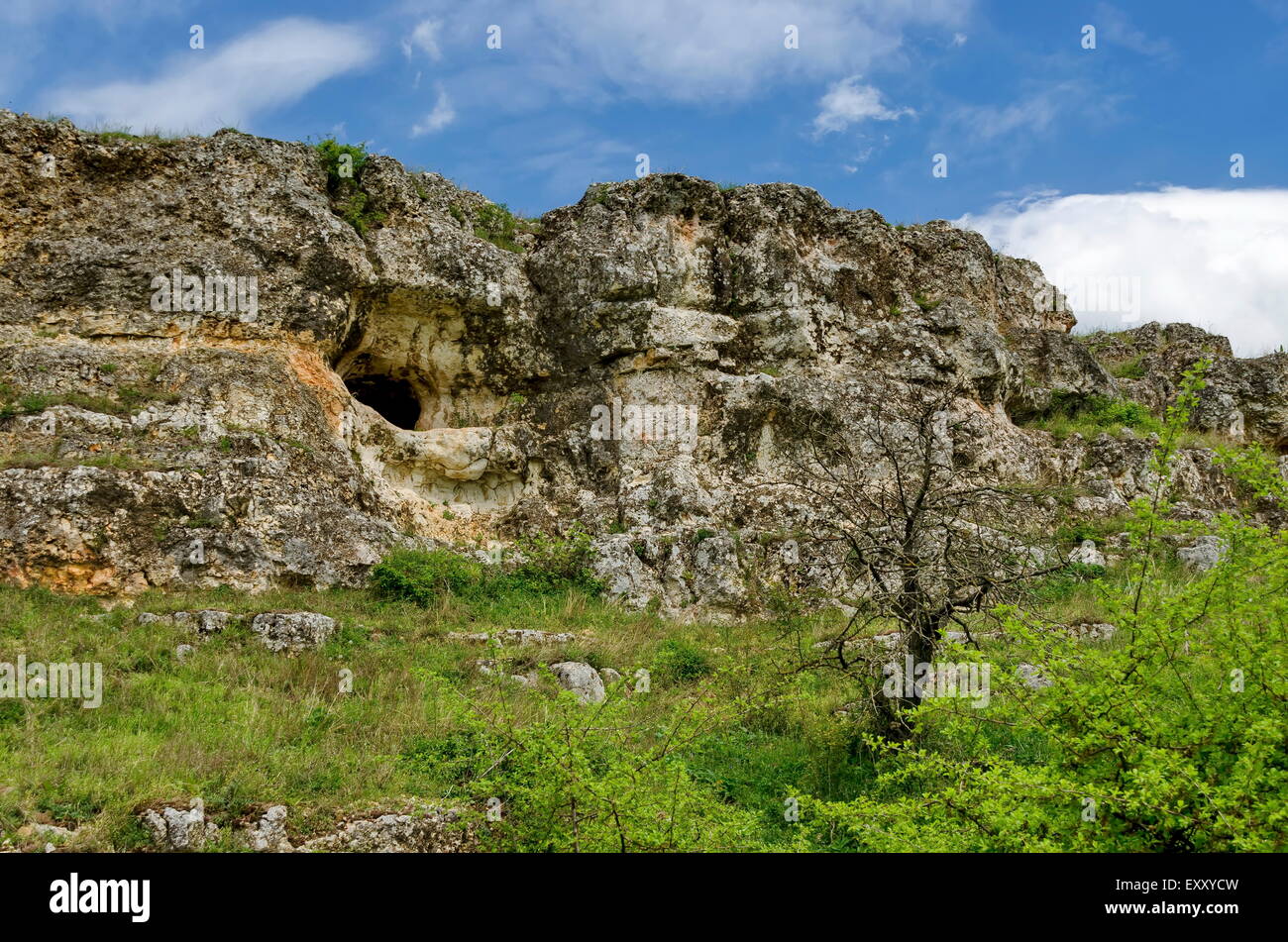 General view toward sedimentary rock with cave in the field, Ludogorie, Bulgaria Stock Photo