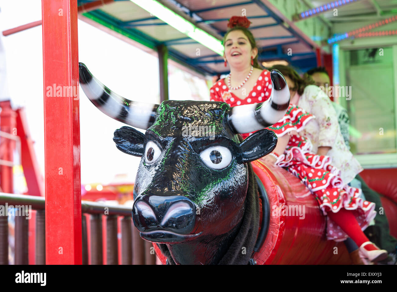 In Seville, Andalucia, Spain, Europe. Children on rotating bull ride in fair ground section at April Feria Festival.  © Paul Qua Stock Photo