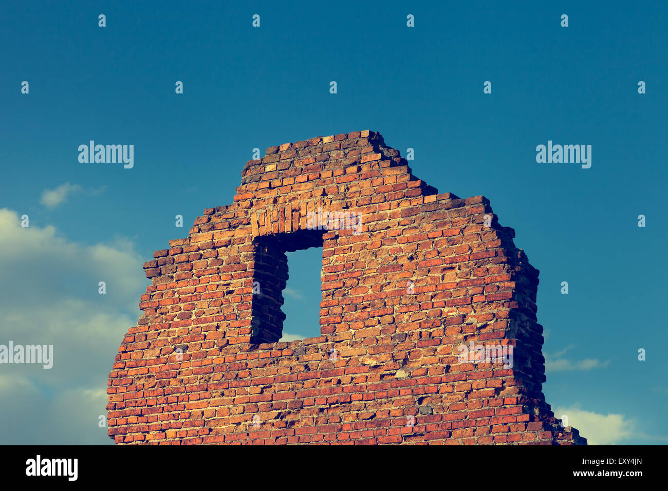 Fragment of ancient ruined building with window on blue sky background. Stock Photo