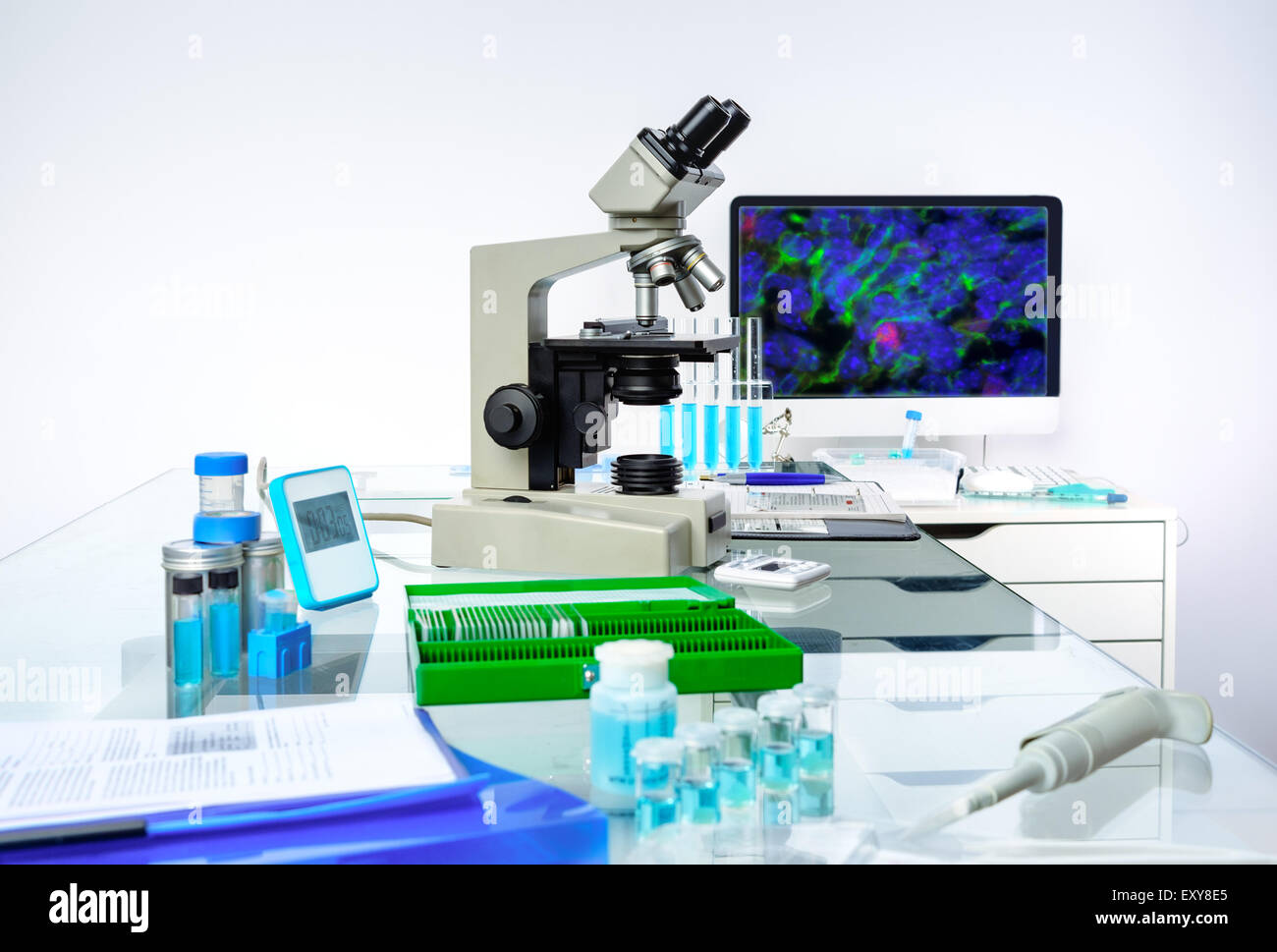 Microscopic work station. Microscope, computer monitor with digital fluorescent image and tools for histological staining of tis Stock Photo