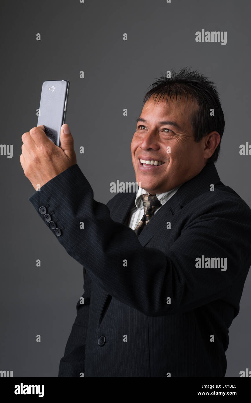 A Hispanic businessman holding taking a selfie with his cell phone. Stock Photo