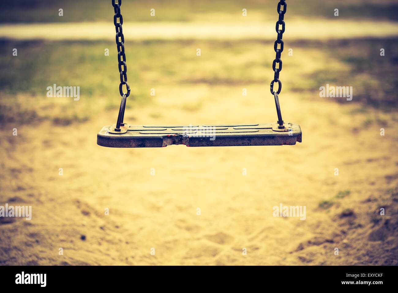 Vintage photo of empty swing on children playground in city. Old fashioned colors photography. Stock Photo