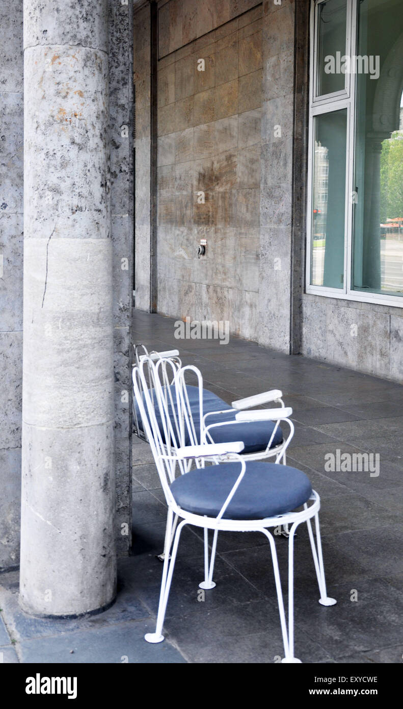 White wrought iron chairs with grey cushions on Karl Marx Allee, Berlin Stock Photo