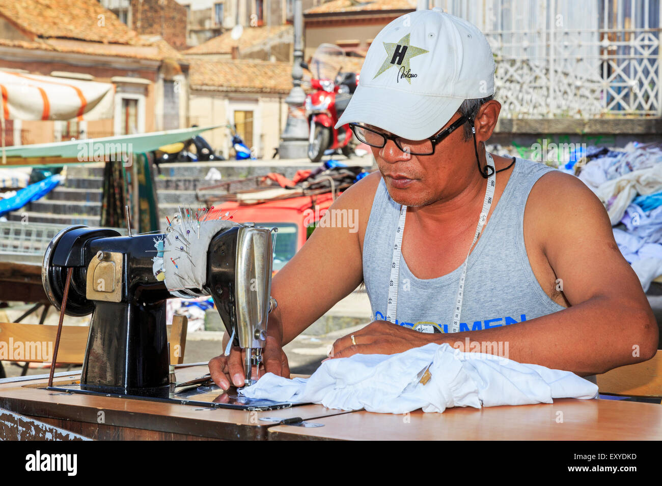 Man doing tailoring and sewing work at the street market, Catania