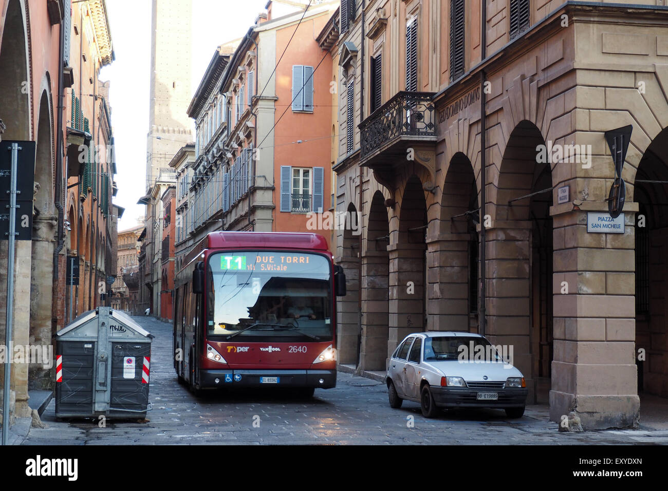 Red bus and a white car in a street of Bologna. Stock Photo