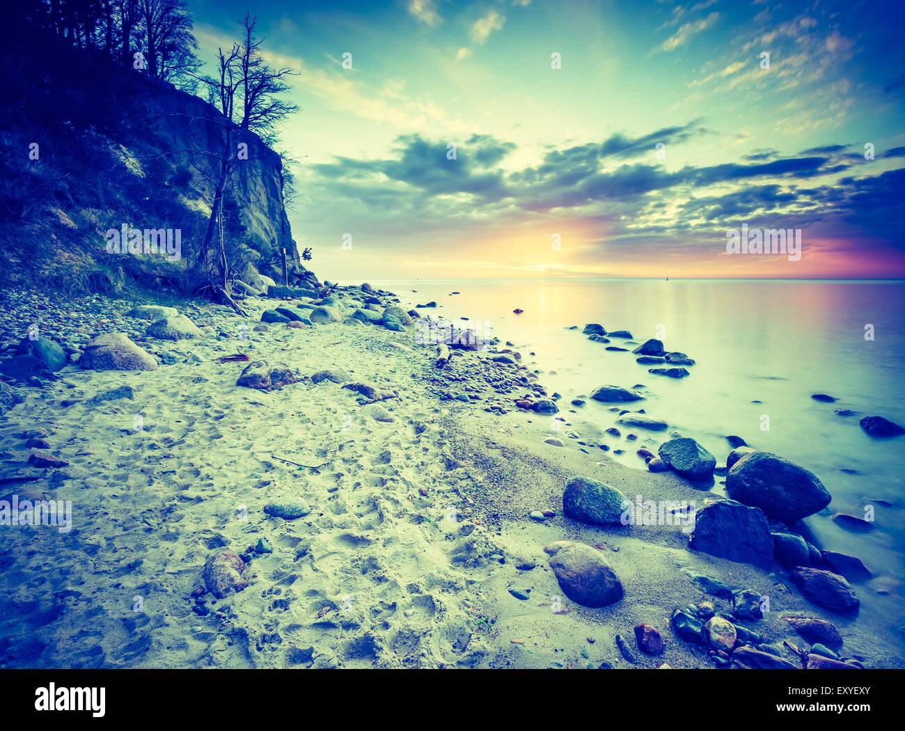 Vintage photo of beautiful rocky sea shore at sunrise or sunset. Long ...