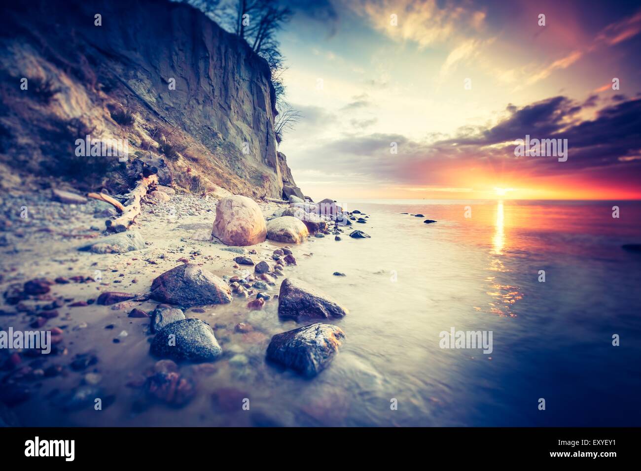 Vintage photo of beautiful rocky sea shore at sunrise or sunset. Long ...
