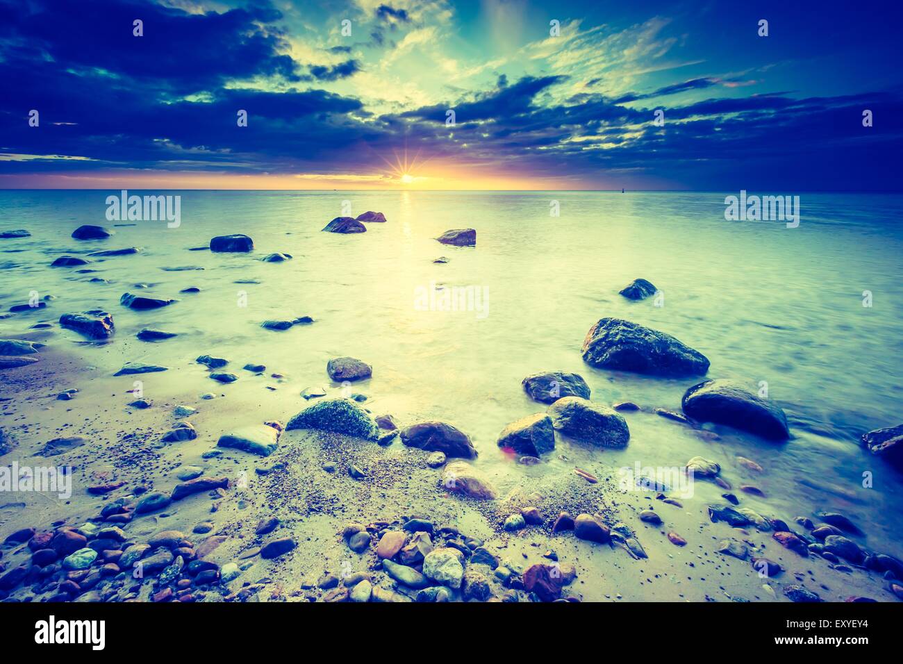 Vintage photo of beautiful rocky sea shore at sunrise or sunset. Long ...