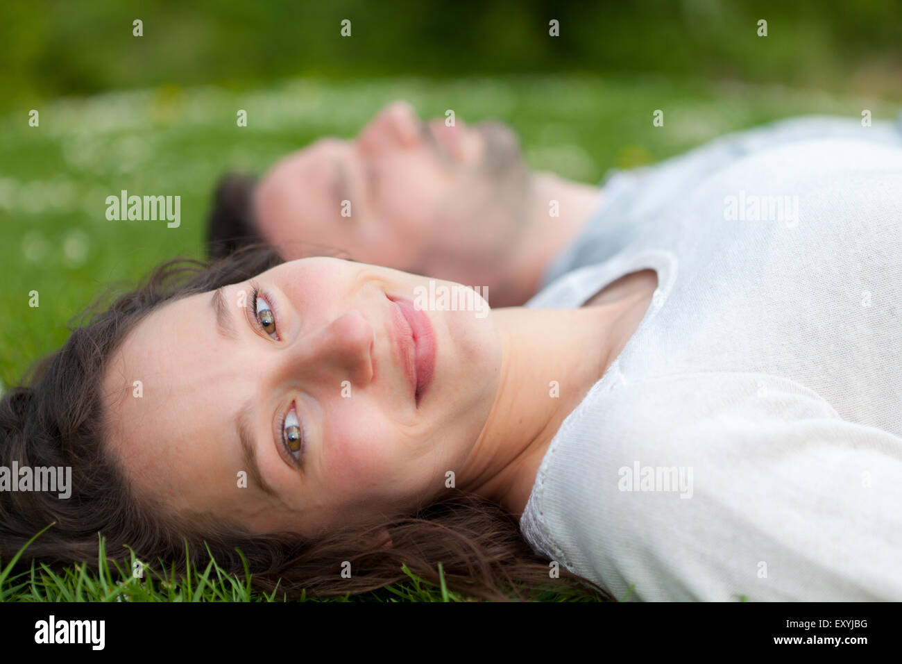 View of an Attractive couple lying in grass at the park Stock Photo - Alamy