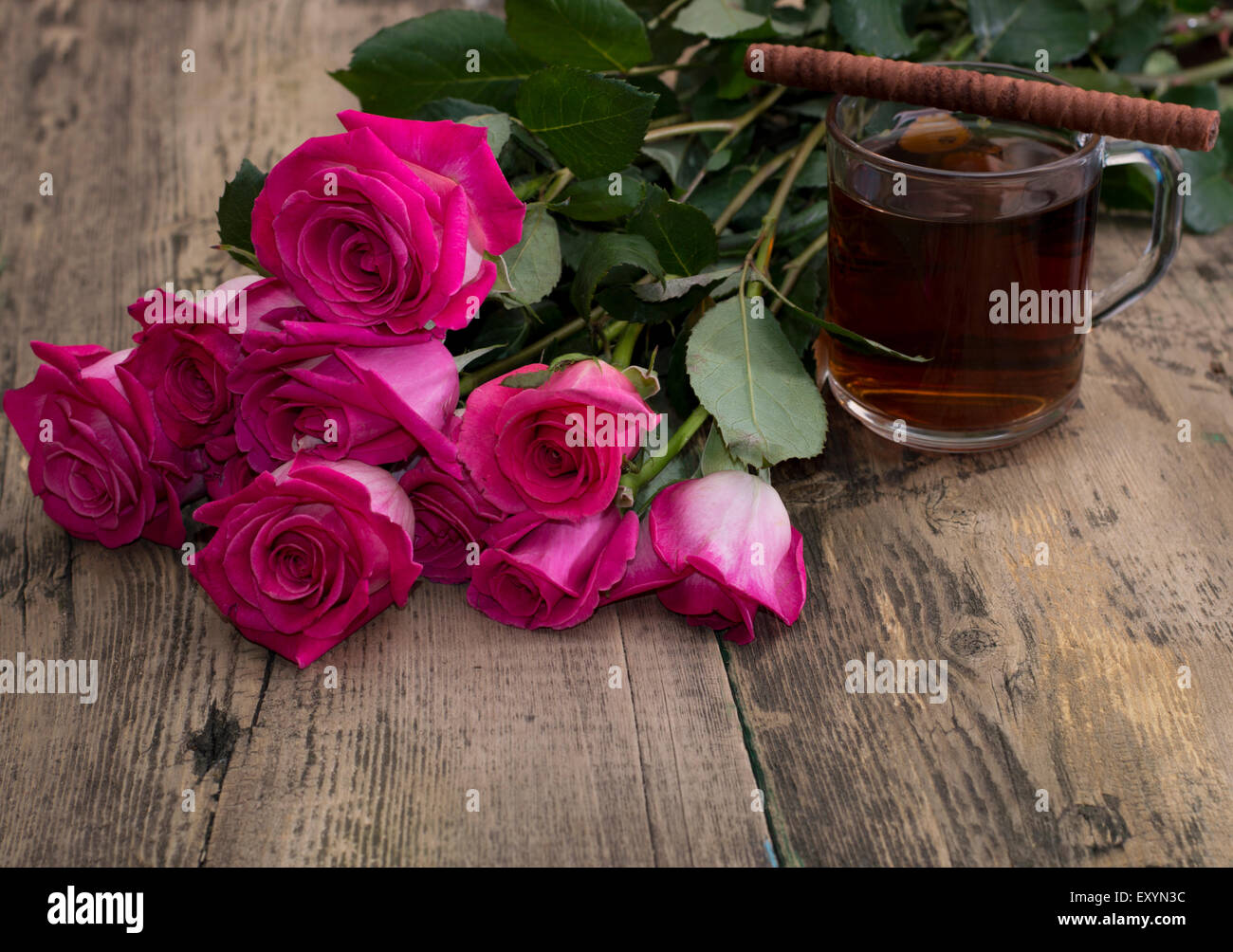 glass of strong tea, cookies and bouquet of scarlet roses Stock Photo