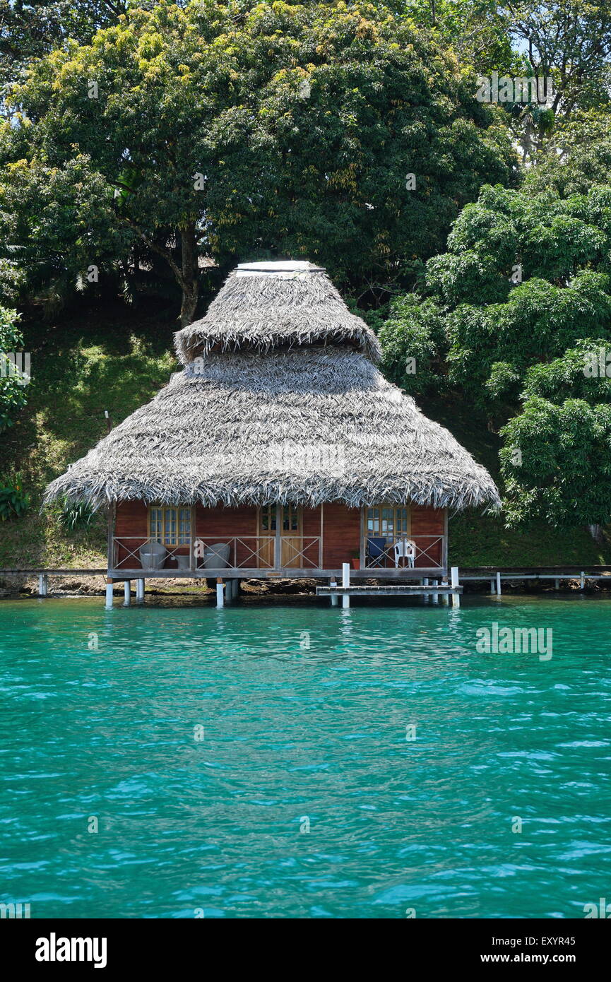 Tropical wooden bungalow with thatched roof over water of the Caribbean sea in Central America, Panama, Bocas del Toro Stock Photo