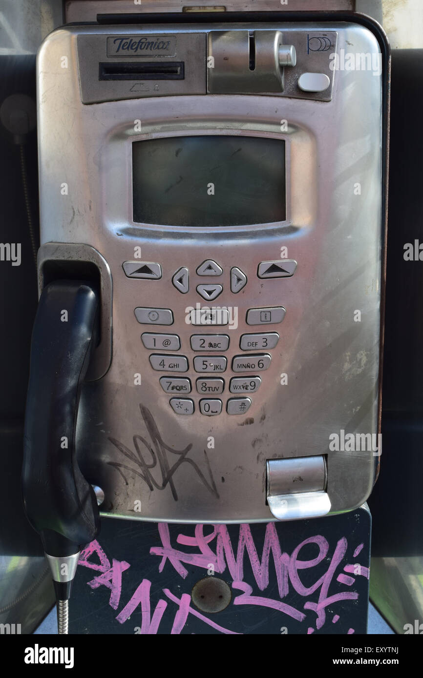 A public telephone with some tags on it. a classic stainless steel design. Stock Photo