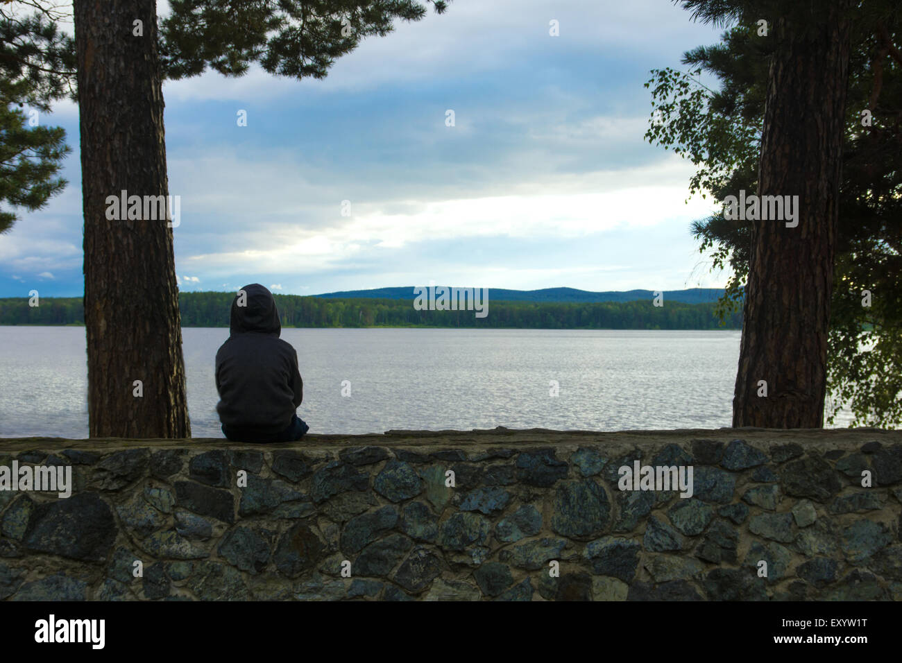 Child alone at the lake, sad cloudy evening Stock Photo
