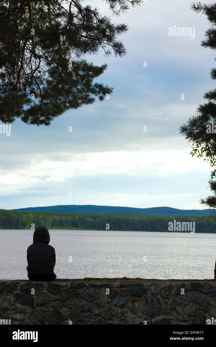 Child alone at the beautiful lake, sad cloudy evening Stock Photo
