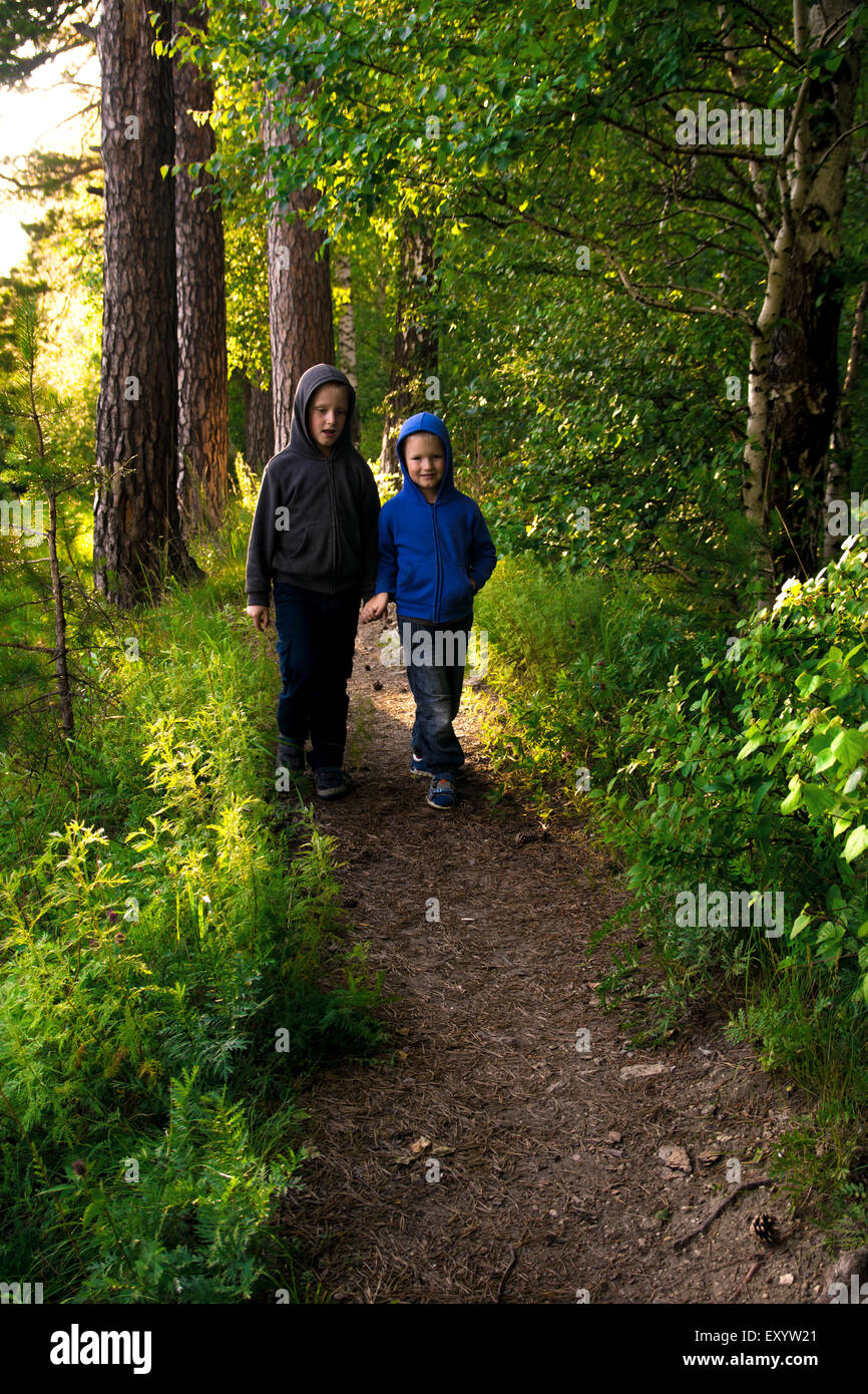 Children (brothers, friends) walking, hiking in wild green summer forest Stock Photo