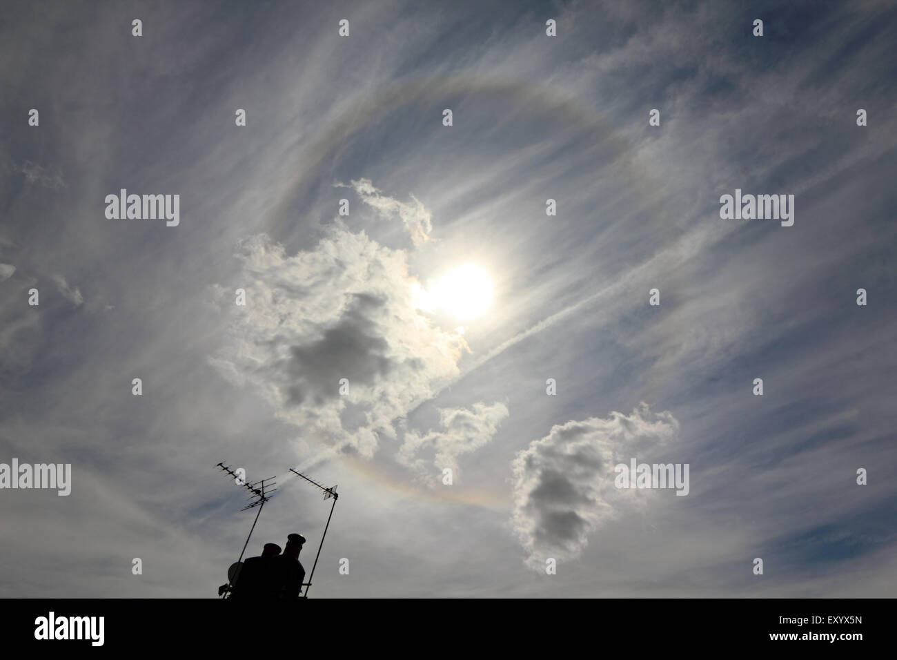 Epsom, Surrey, UK. 18th July, 2015. As a vale of thin cloud drifts across the sky, a halo is visible around the sun. The circular (or 22 degree) halo is an optical phenomenon produced by light interacting with ice crystals suspended in the atmosphere, creating a rainbow effect around the sun. Credit:  Julia Gavin UK/Alamy Live News Stock Photo