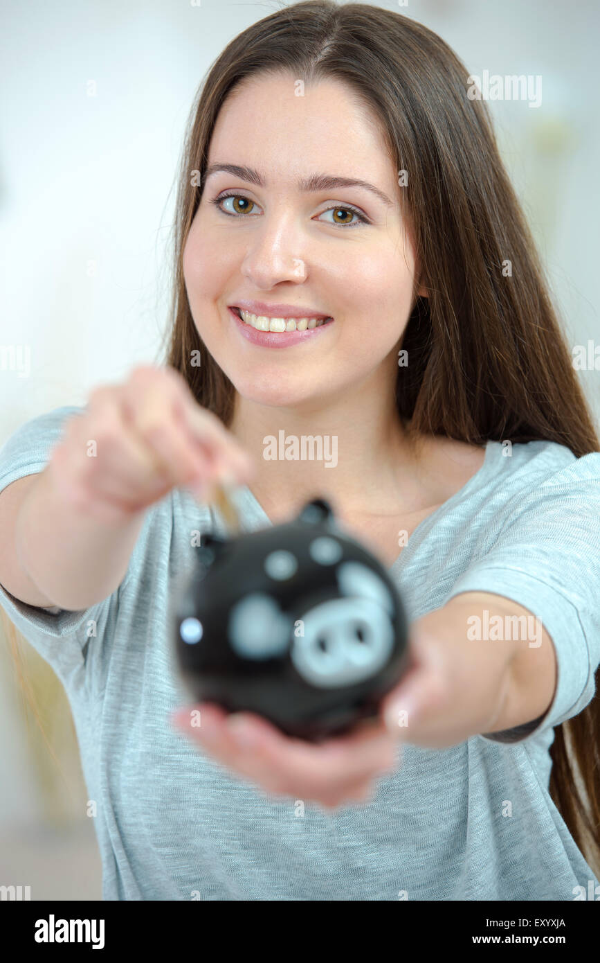 Woman putting coin into a piggy bank Stock Photo - Alamy