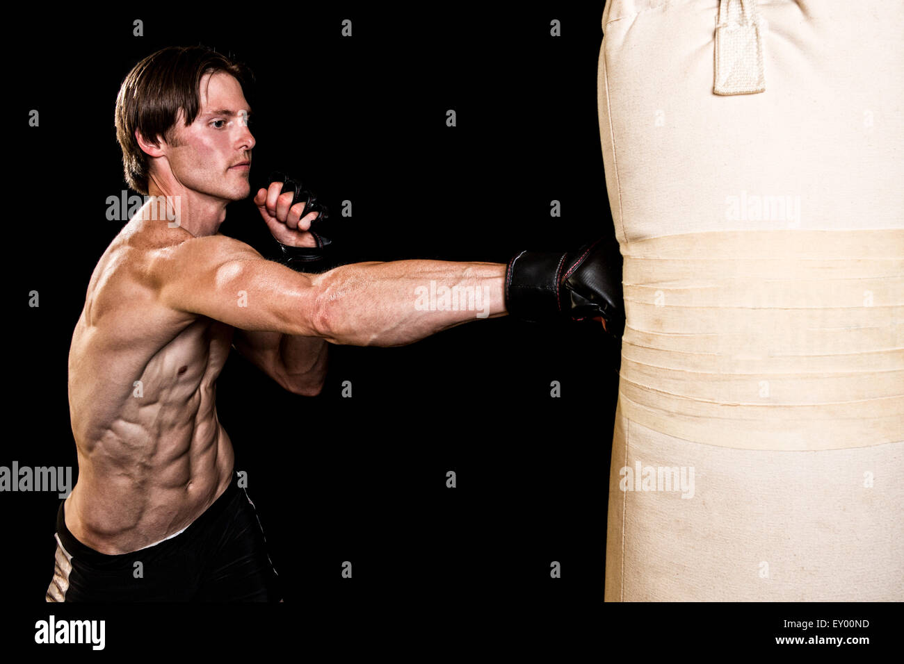 Young adult martial artist with heavy bag. Studio shot over black. Stock Photo