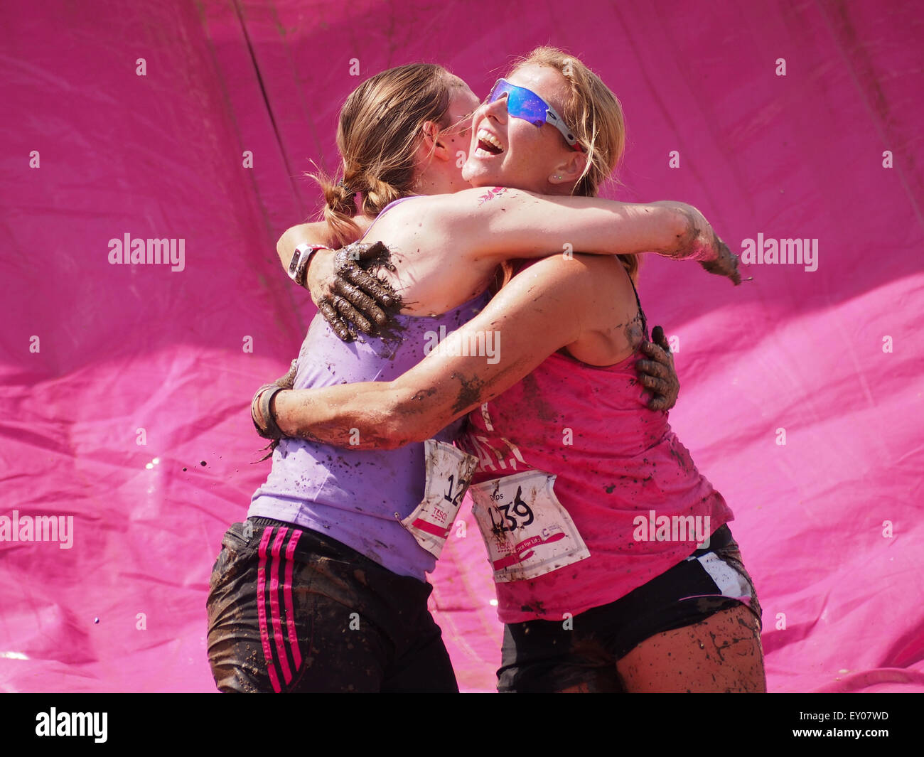 Portsmouth, UK. 18th July, 2015. Two  participants in the Race For Life - Pretty muddy hug each other at the end of the final obstacle of the race. The Race for Life Pretty Muddy event is open to females only and consists of a 5K mud covered obstacle course Credit:  simon evans/Alamy Live News Stock Photo