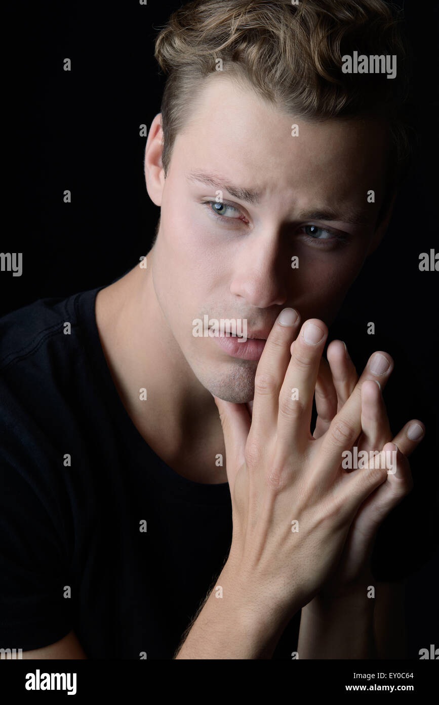 A sad man looking vulnerable and worried. A dark emotional portrait. Stock Photo