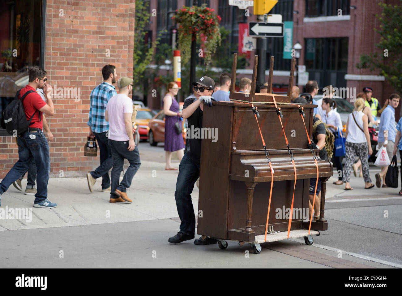 Two guys move piano across busy downtown street Stock Photo Alamy
