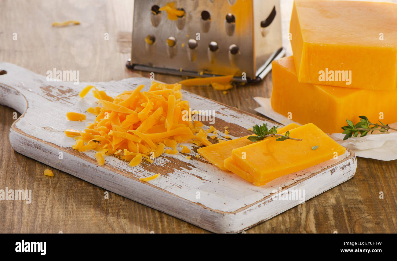 Grated Cheddar Cheese on  wooden Board. Selective focus Stock Photo