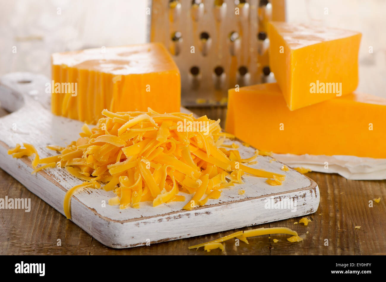 Grated Cheddar Cheese on a Cutting Board. Selective focus Stock Photo