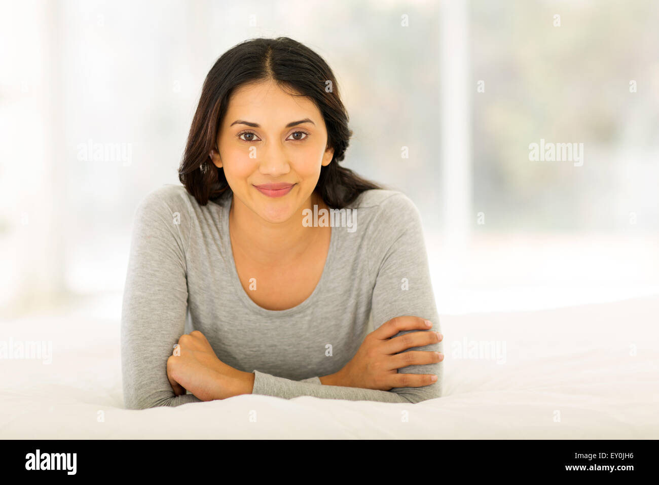 portrait of cute Indian woman lying on bed Stock Photo
