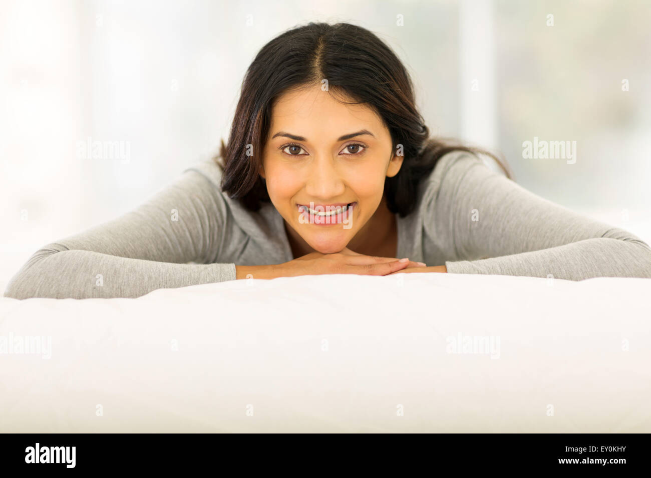 pretty Indian woman lying on bed at home Stock Photo