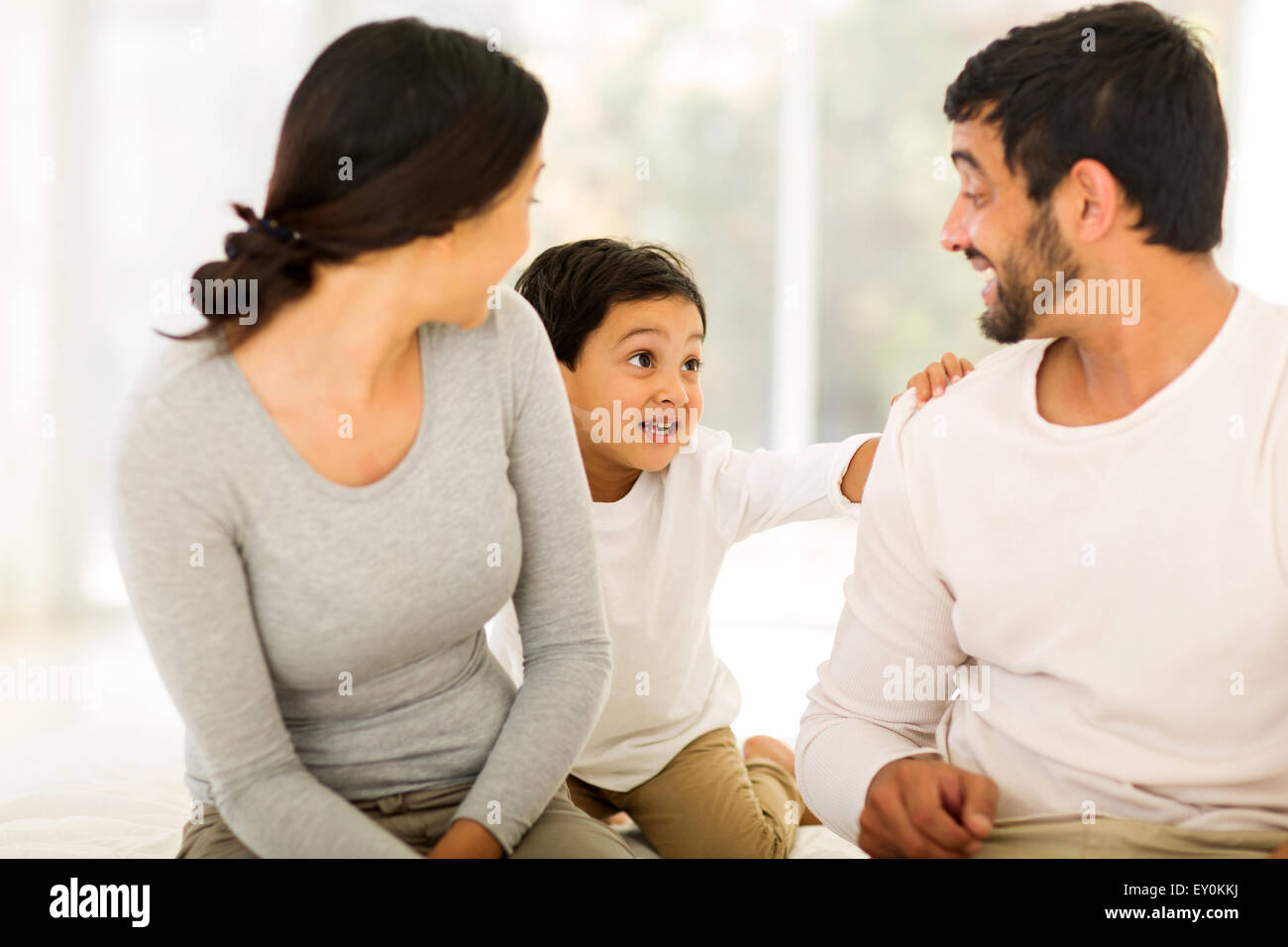 happy young Indian couple with their son sitting on bed at home Stock ...