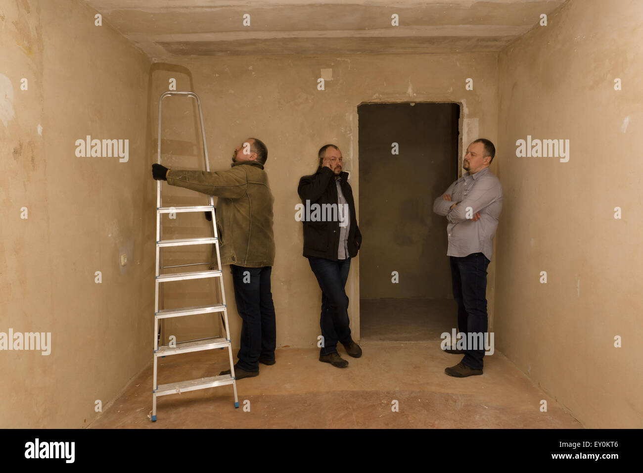 three men of the twin plan repair in the destroyed apartment Stock Photo