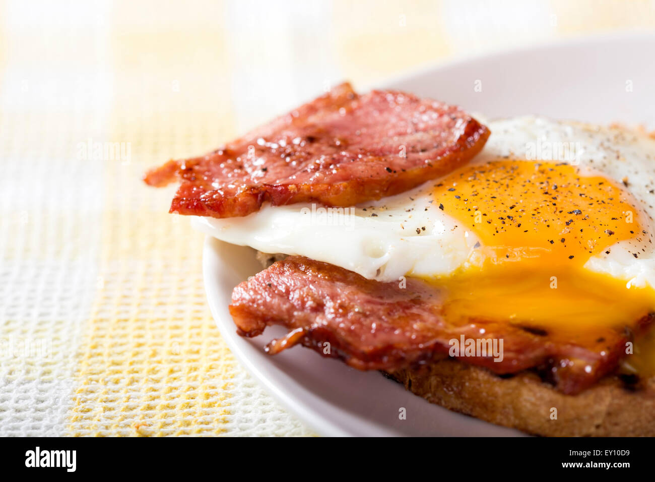 Toast with fried eggs and bacon on a white plate Stock Photo
