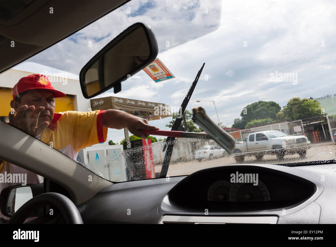 Worker cleaning the front windshield at a Shell Petrol Station