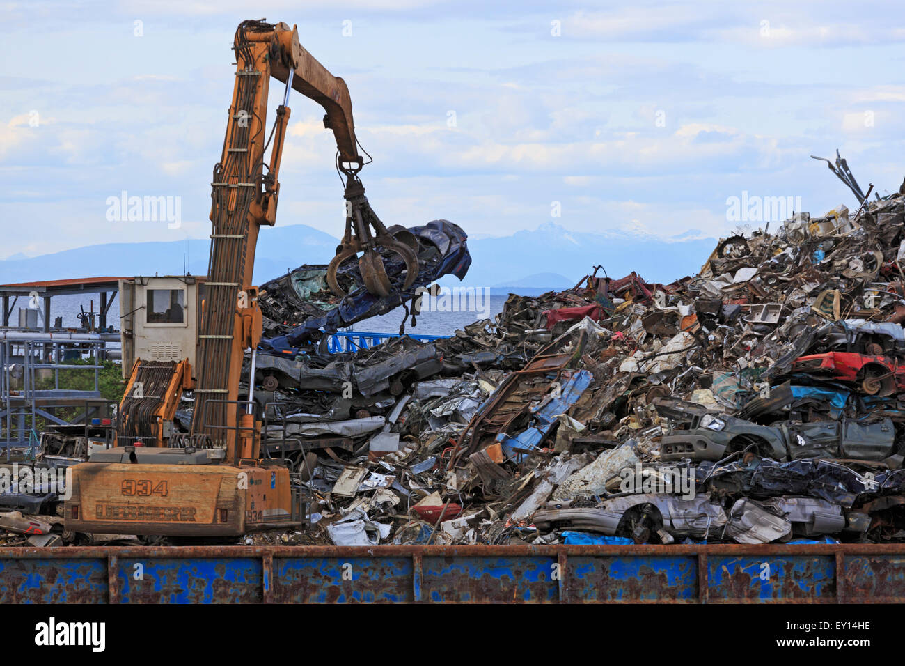 Machine loading scrap metal onto barge, Duke Point, Vancouver Island, British Columbia Stock Photo