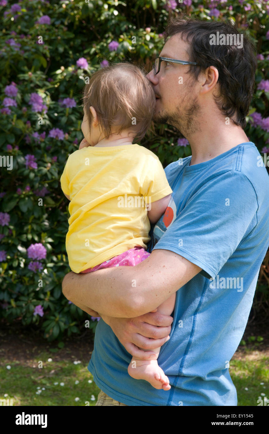 Baby girl being comforted by her father in the garden Stock Photo