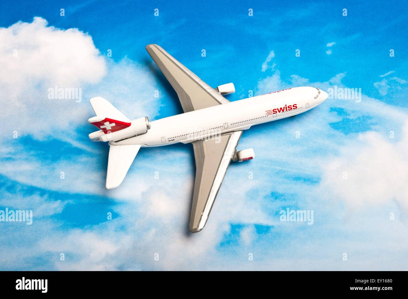 miniature toy airplane Swissair on a printed sky background Stock Photo
