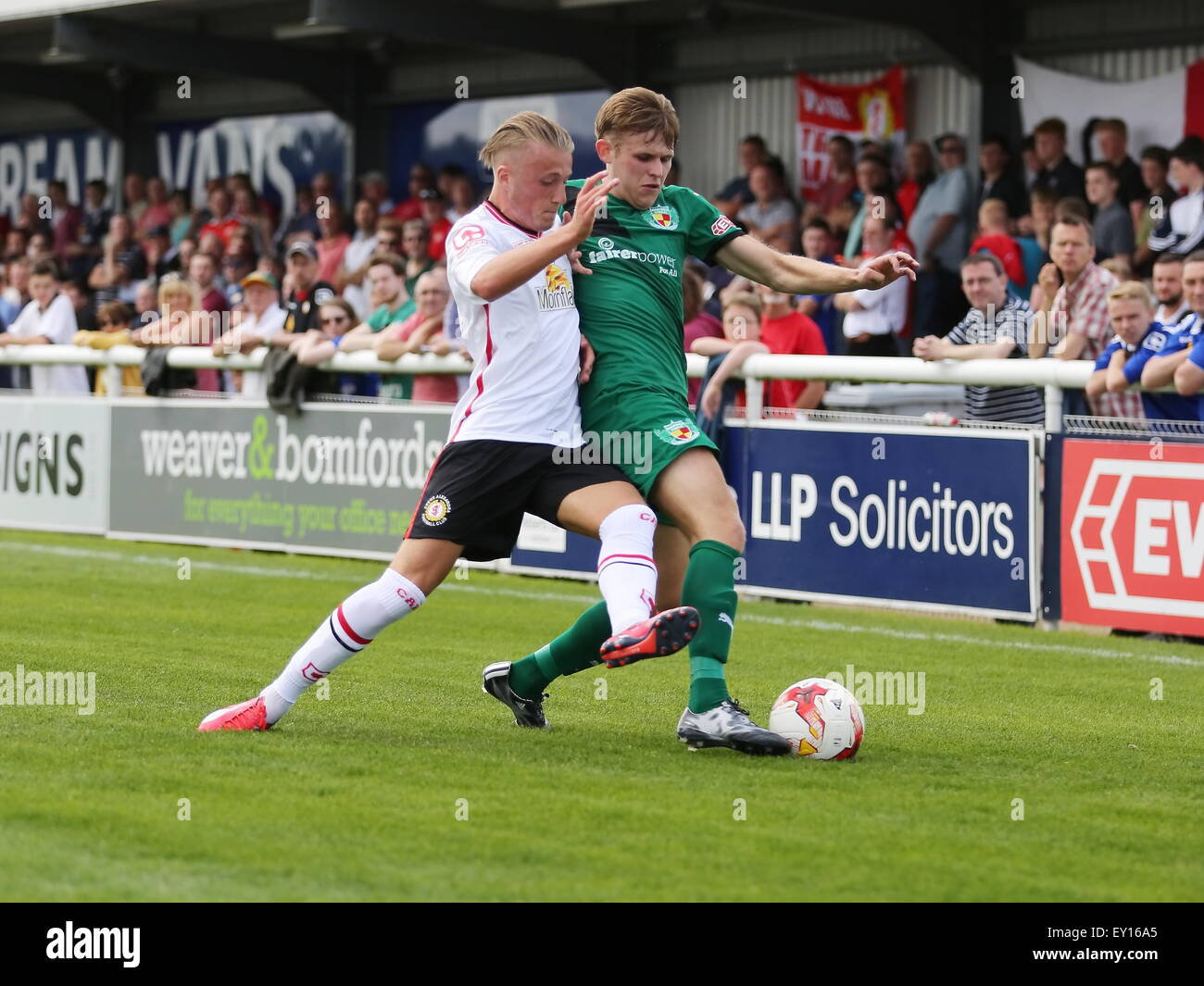 Nantwich, UK. 19th July, 2015. Crewe Alexandra's George Cooper battles for the ball with Nantwich Town's Andy White during the pre-season friendly match at The Weaver Stadium, Nantwich as Nantwich Town entertained Crewe Alexandra. Credit:  SJN/Alamy Live News Stock Photo