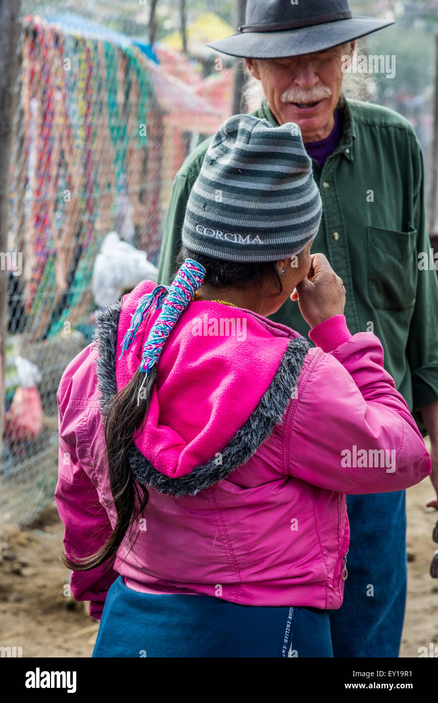 A native woman negotiating with a western tourist at local market. Otavalo, Ecuador. Stock Photo