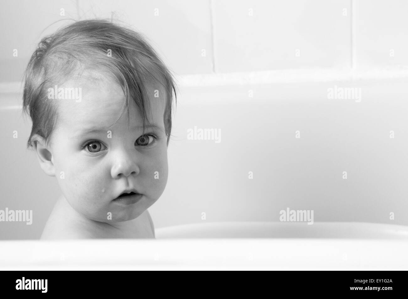 Black and white portrait of baby girl in baby bath looking at the camera Stock Photo