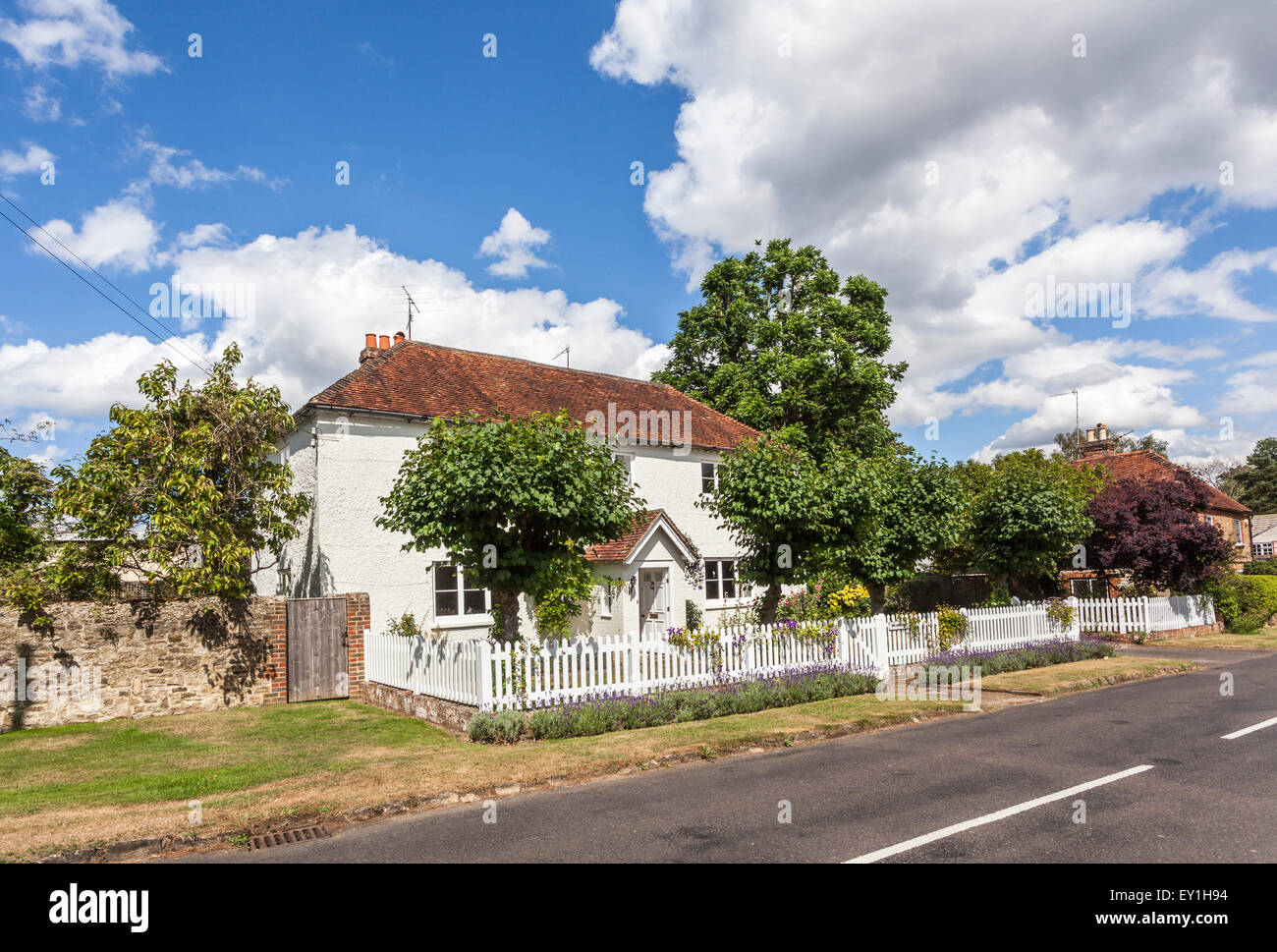 Pretty white cottage with picket fence in Eashing, Shackleford, a small village in Surrey, south-east England on a summer's day with blue sky Stock Photo