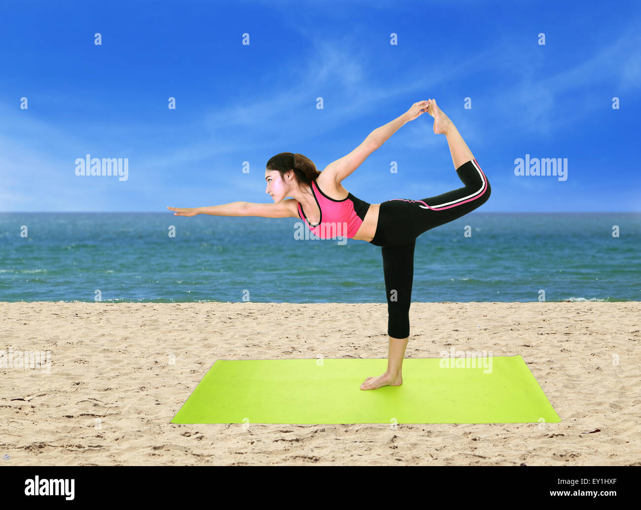 Young woman doing yoga exercise with yoga mat on the beach Stock Photo