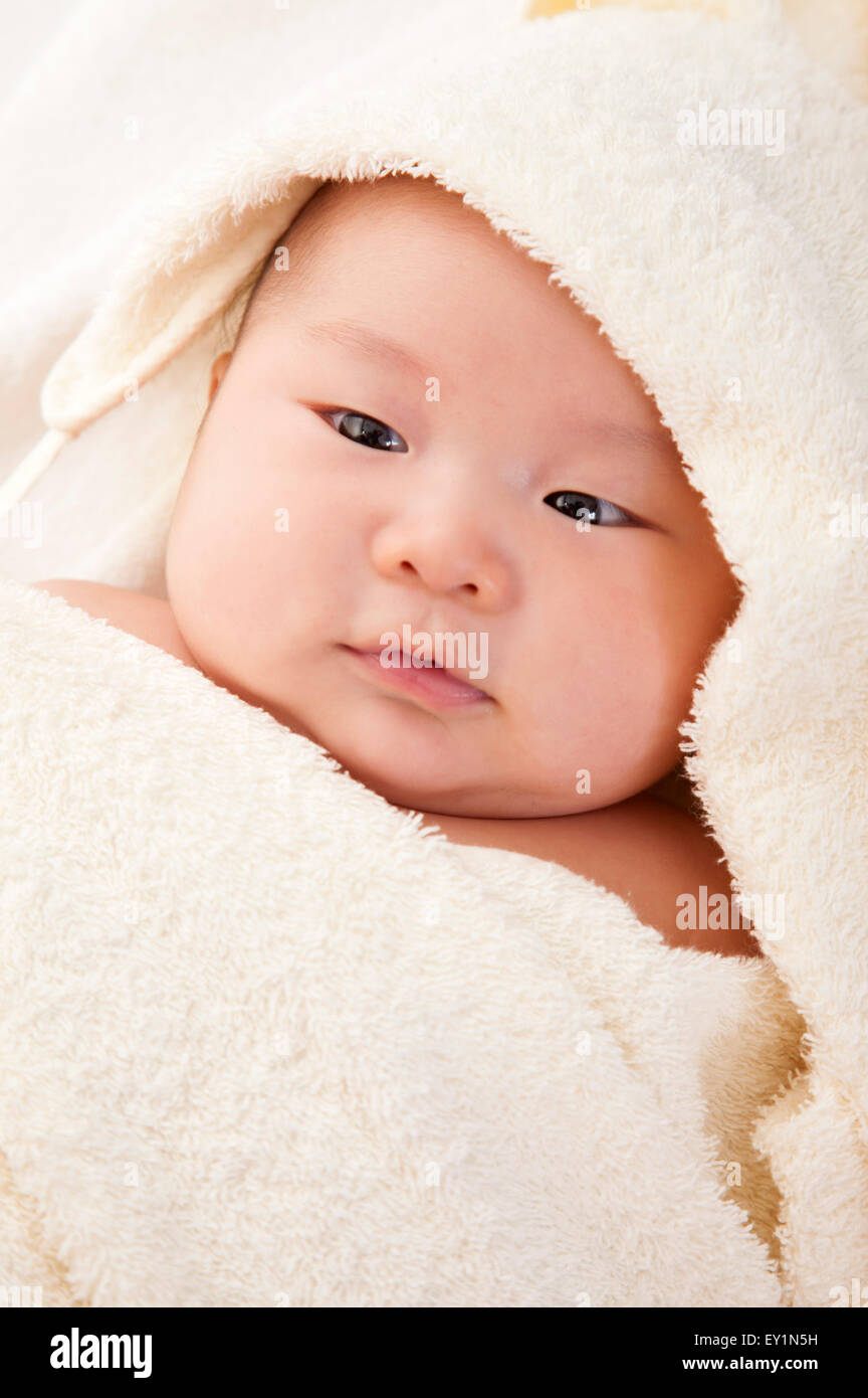 Baby boy wrapped in a blanket and looking away, Stock Photo