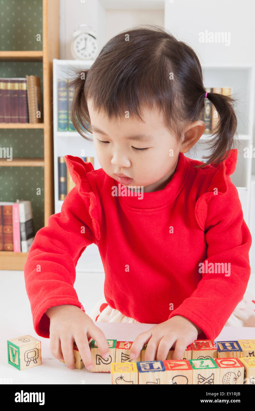 Little girl playing toy and looking down Stock Photo - Alamy